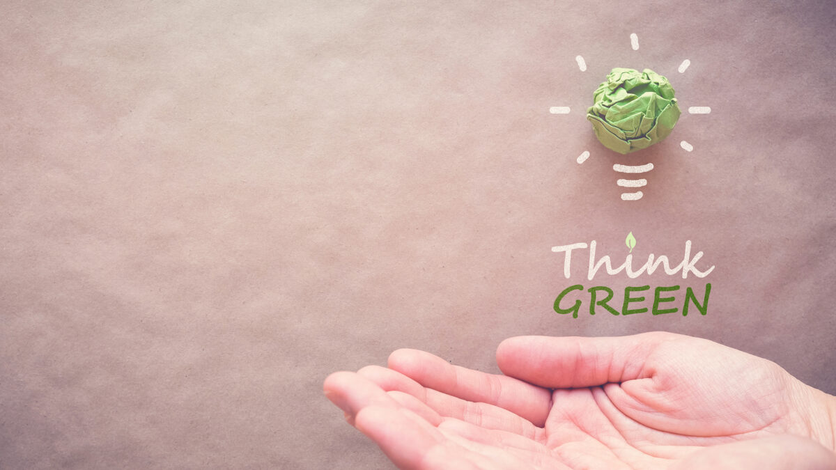 Green paper light bulb with Think Green over hands eco energy saving concept