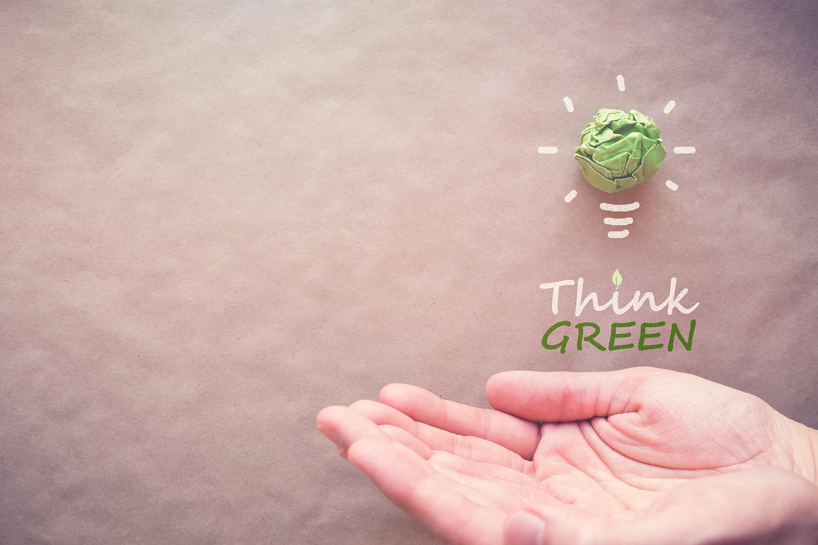 Groene papieren lamp met Think Green over handen eco-energiebesparend concept