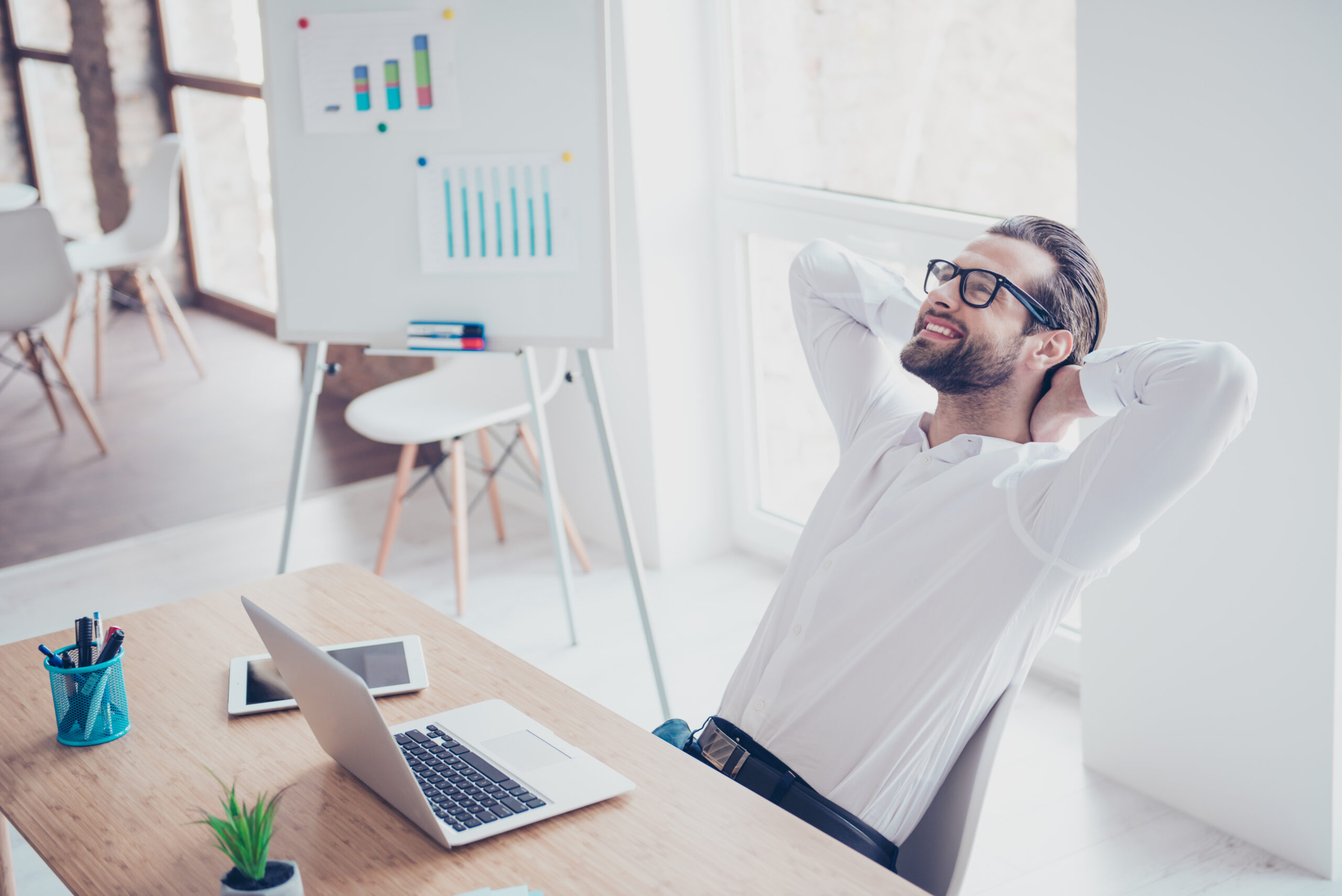 Uomo d'affari sorridente e felice con occhiali e camicia bianca che si rilassa in ufficio dopo una dura giornata di lavoro